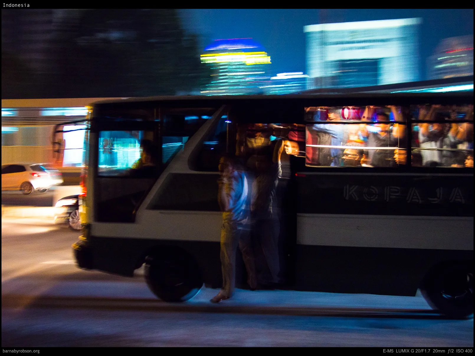 Motion-blurred bus at night with passengers and city lights.