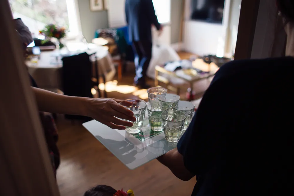 Hands exchanging a tray of small glasses of drinks.