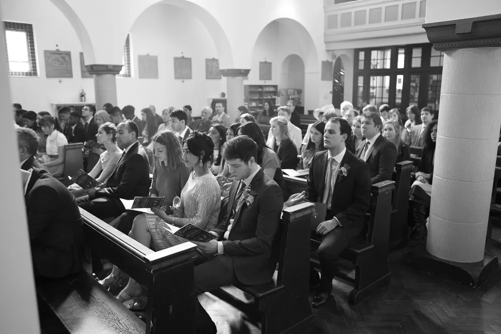 Formally dressed people sitting in pews at a church ceremony.