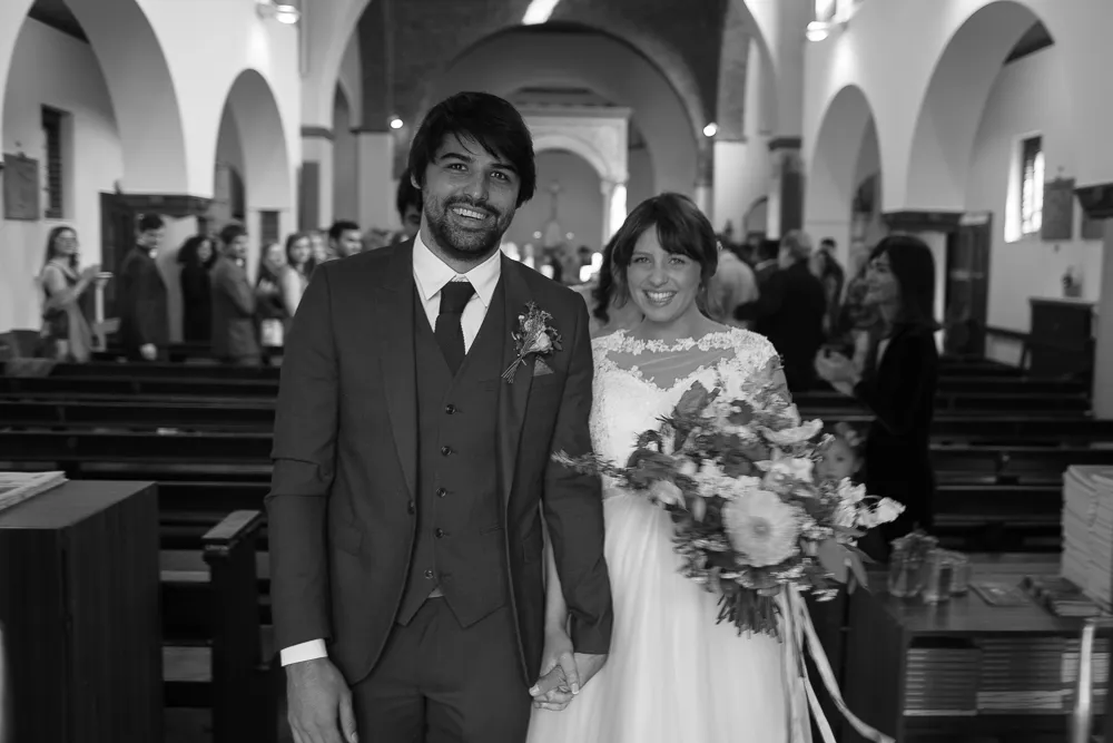Smiling bride and groom holding hands in a church aisle.