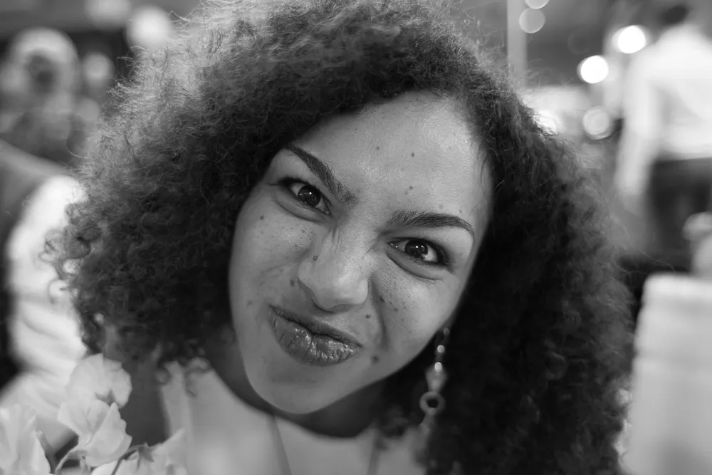 Black and white portrait of a woman with curly hair making a funny face.