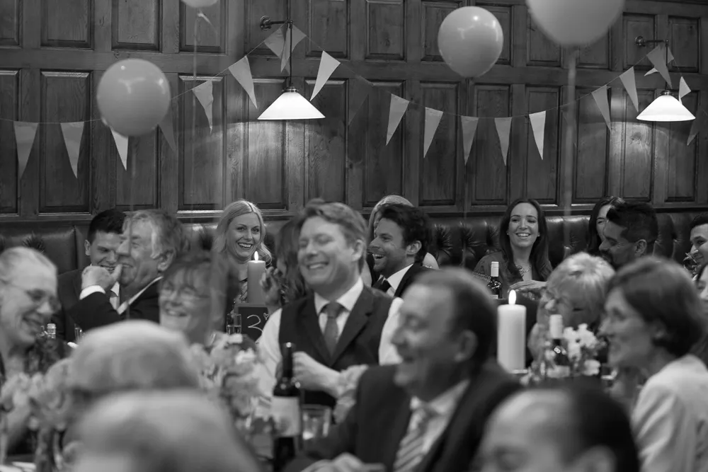 Guests laughing and smiling at a party with balloons and bunting.