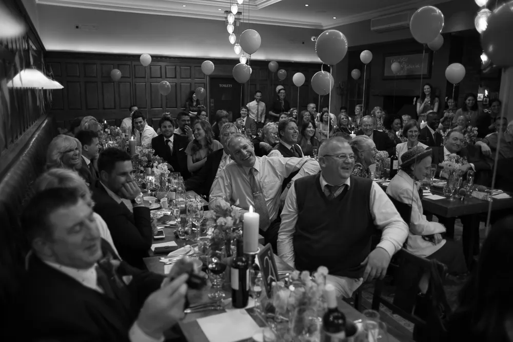 Smiling guests at a lively dinner party with balloons.
