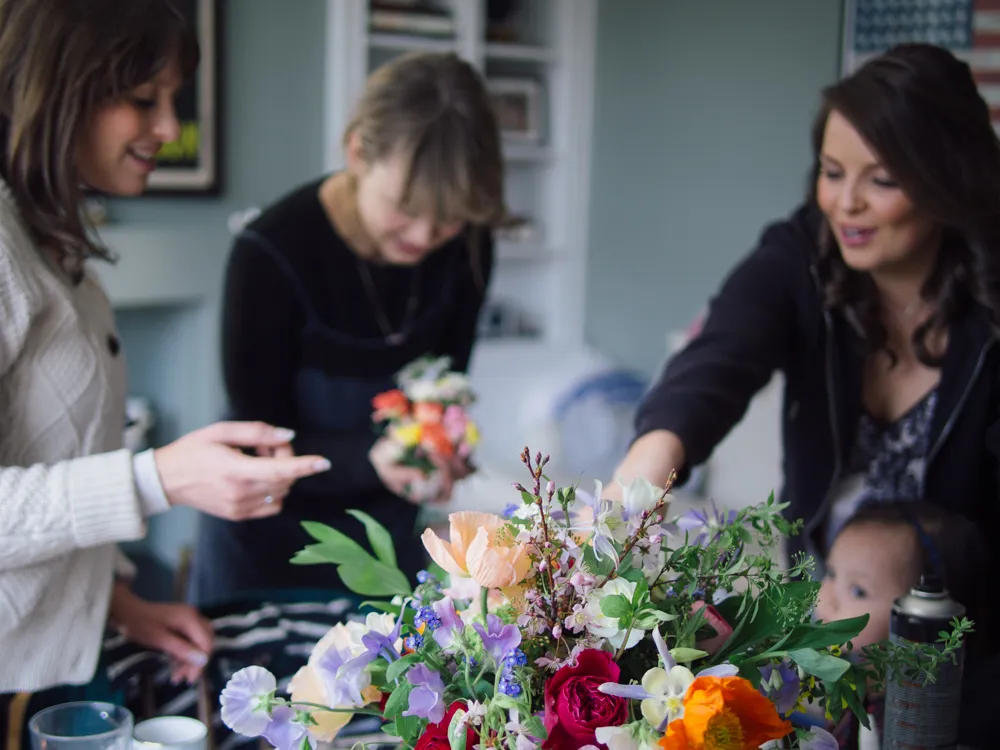 Three women and a baby arranging colourful flowers.
