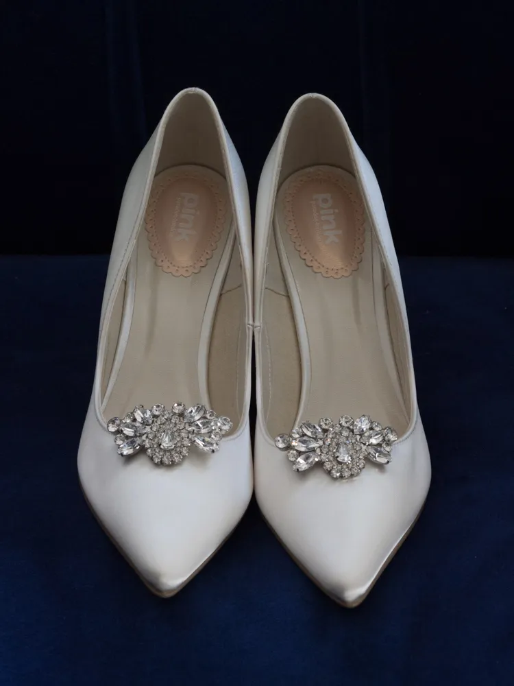 White satin pointed heels with ornate crystal embellishments.
