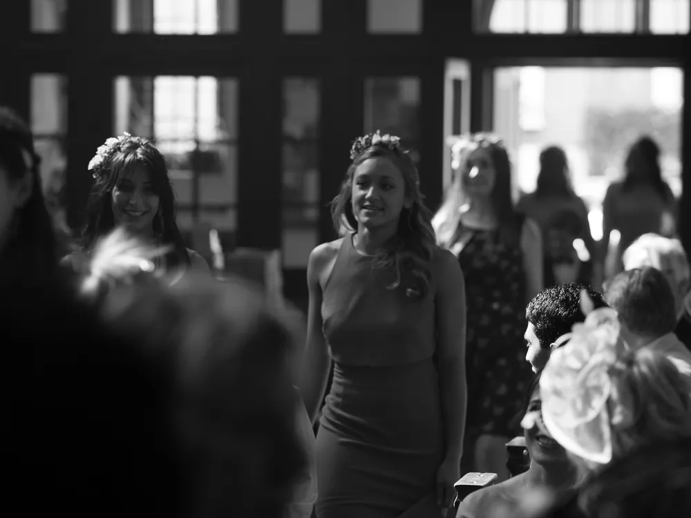 Black and white: Two women with floral headpieces smile at a gathering.