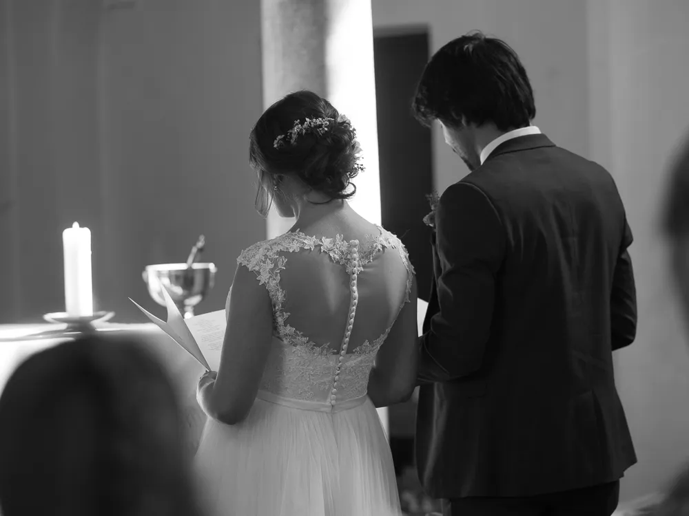 Black and white: Bride and groom from behind at ceremony, candle and chalice.