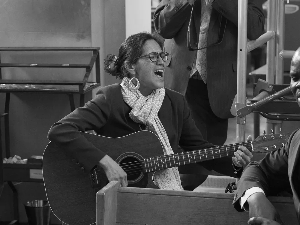 Black and white: woman singing and playing an acoustic guitar.