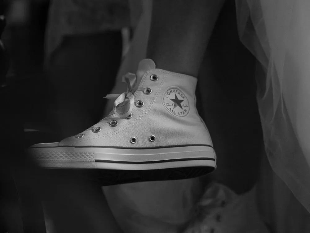 Monochrome close-up of a white Converse All Star trainer and flowing white fabric.