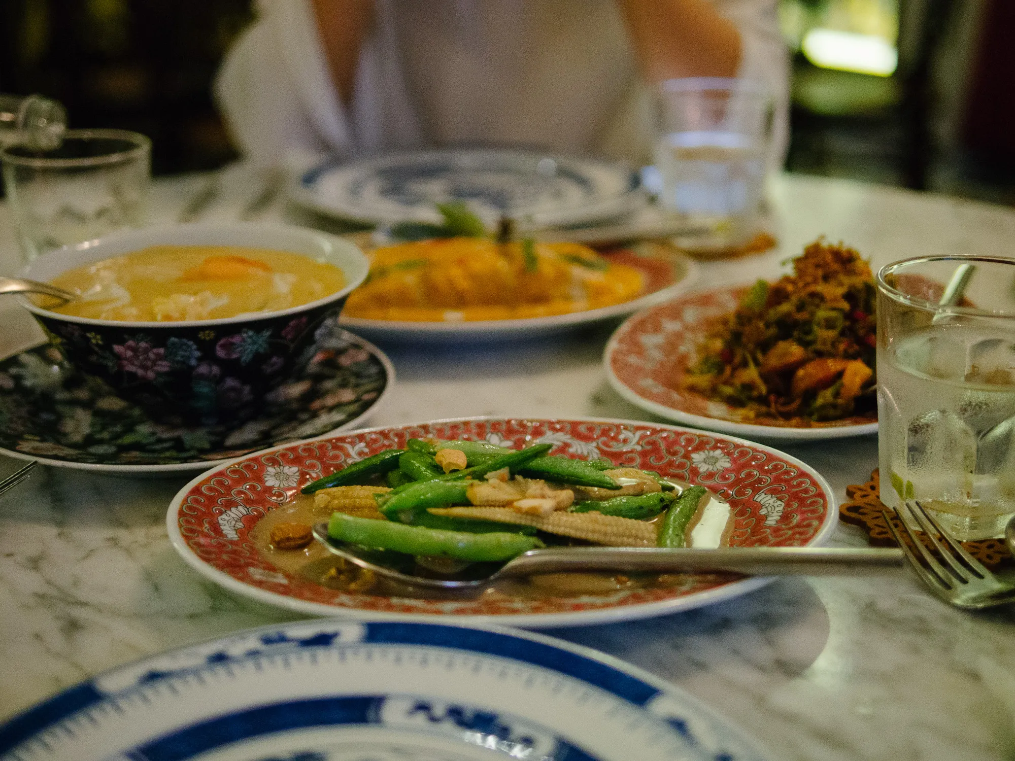 Table laden with various Asian dishes: soup, vegetables, and stir-fries.