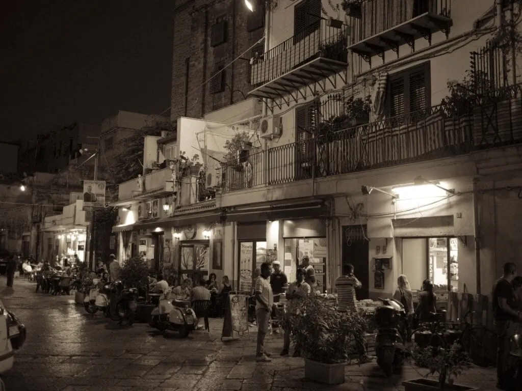 Balconies and bar tables on a Palermo backstreet at night