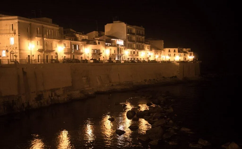 Ortygia's waterfront lamps reflected in the harbour at night