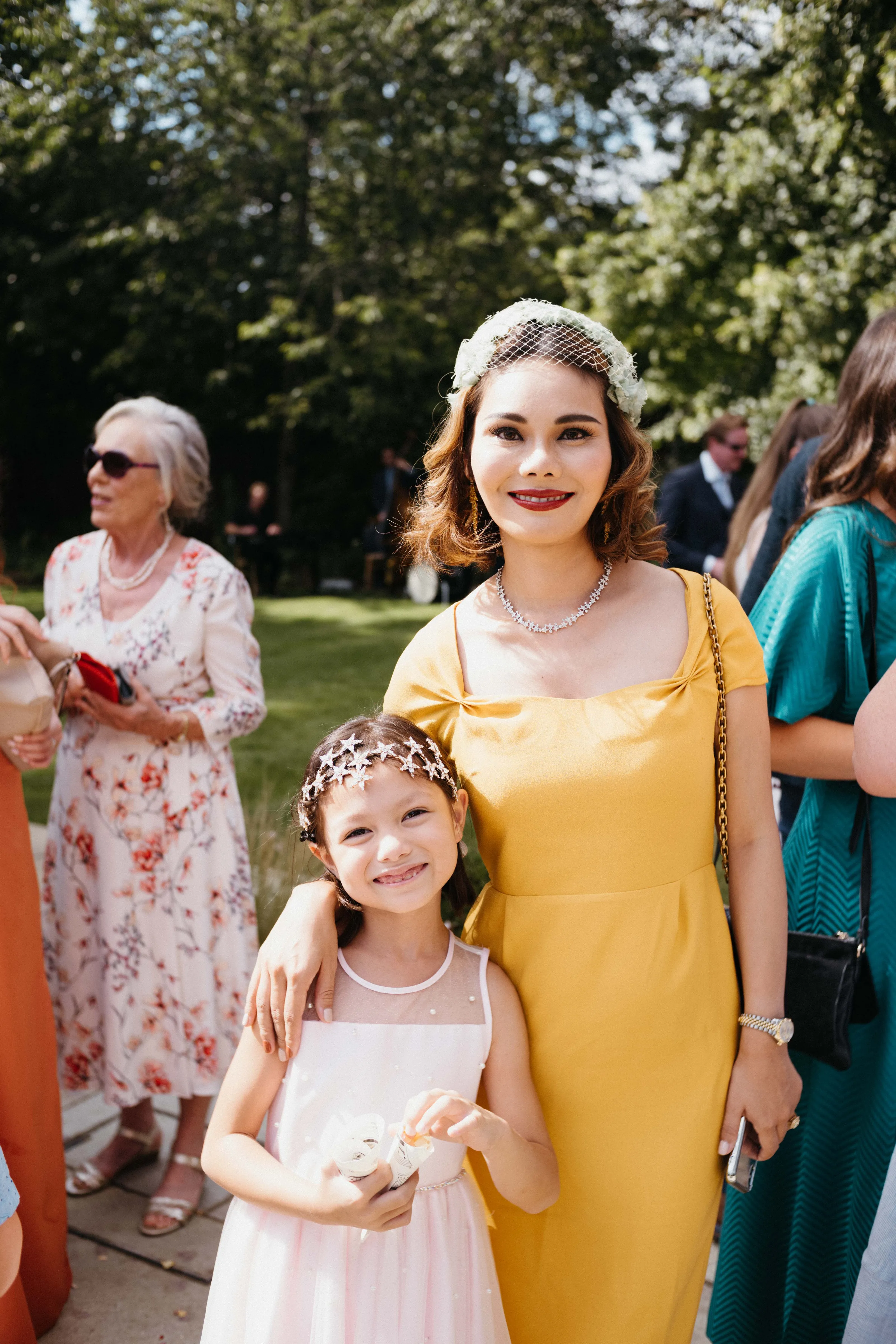 Smiling woman in yellow dress and girl in pink with star headpiece.