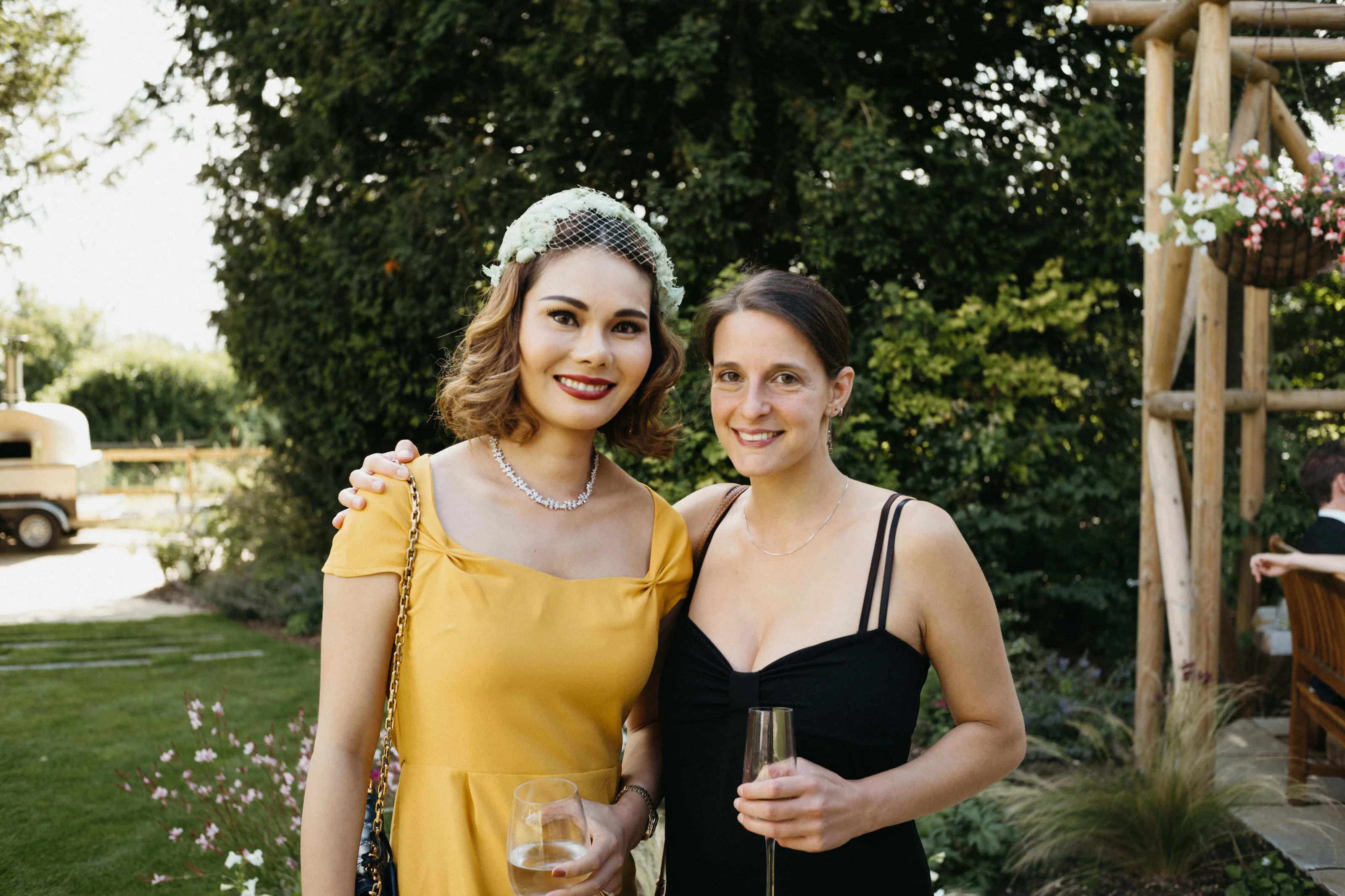 Two smiling women in yellow and black dresses holding drinks.