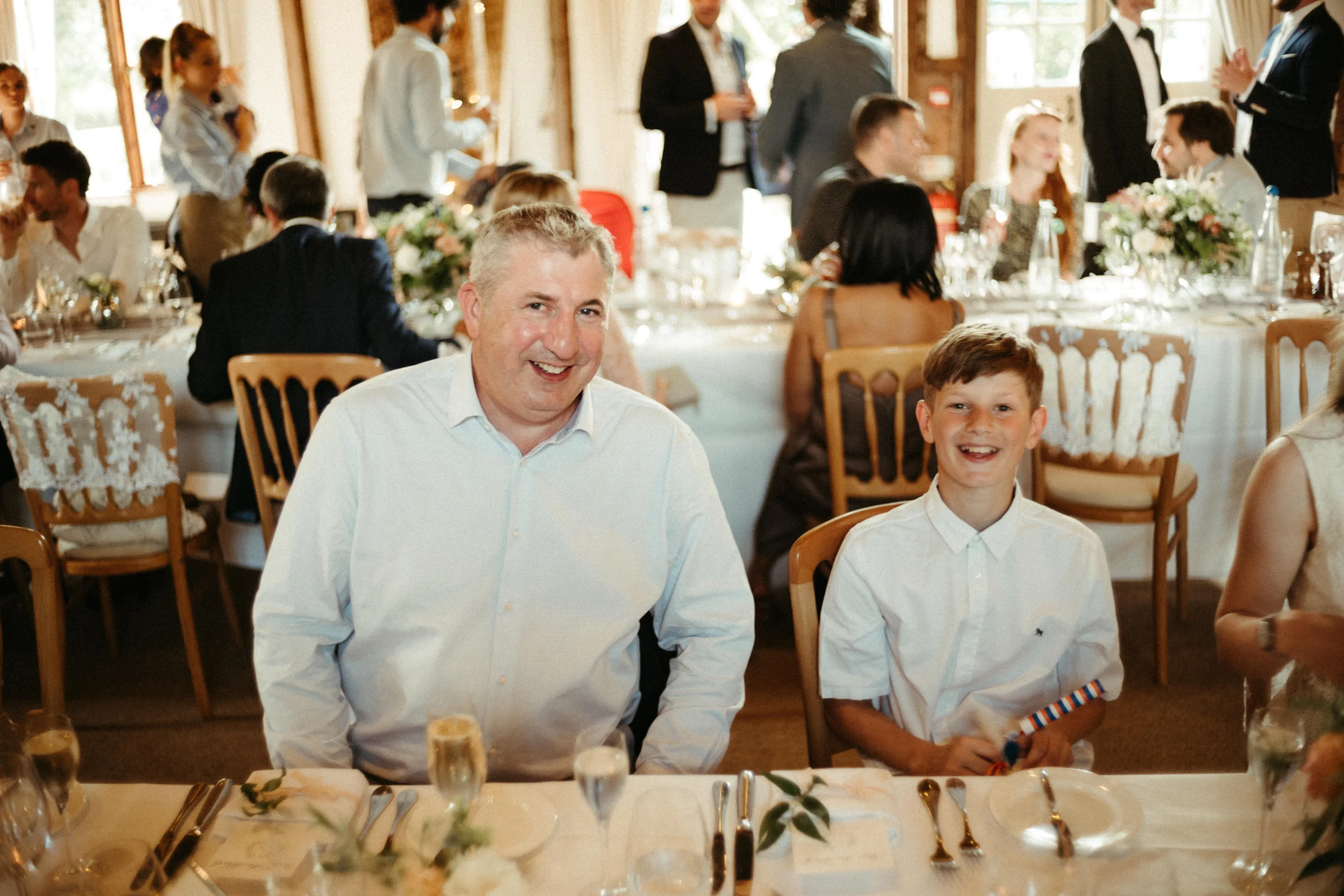Man and boy smiling at a reception table.