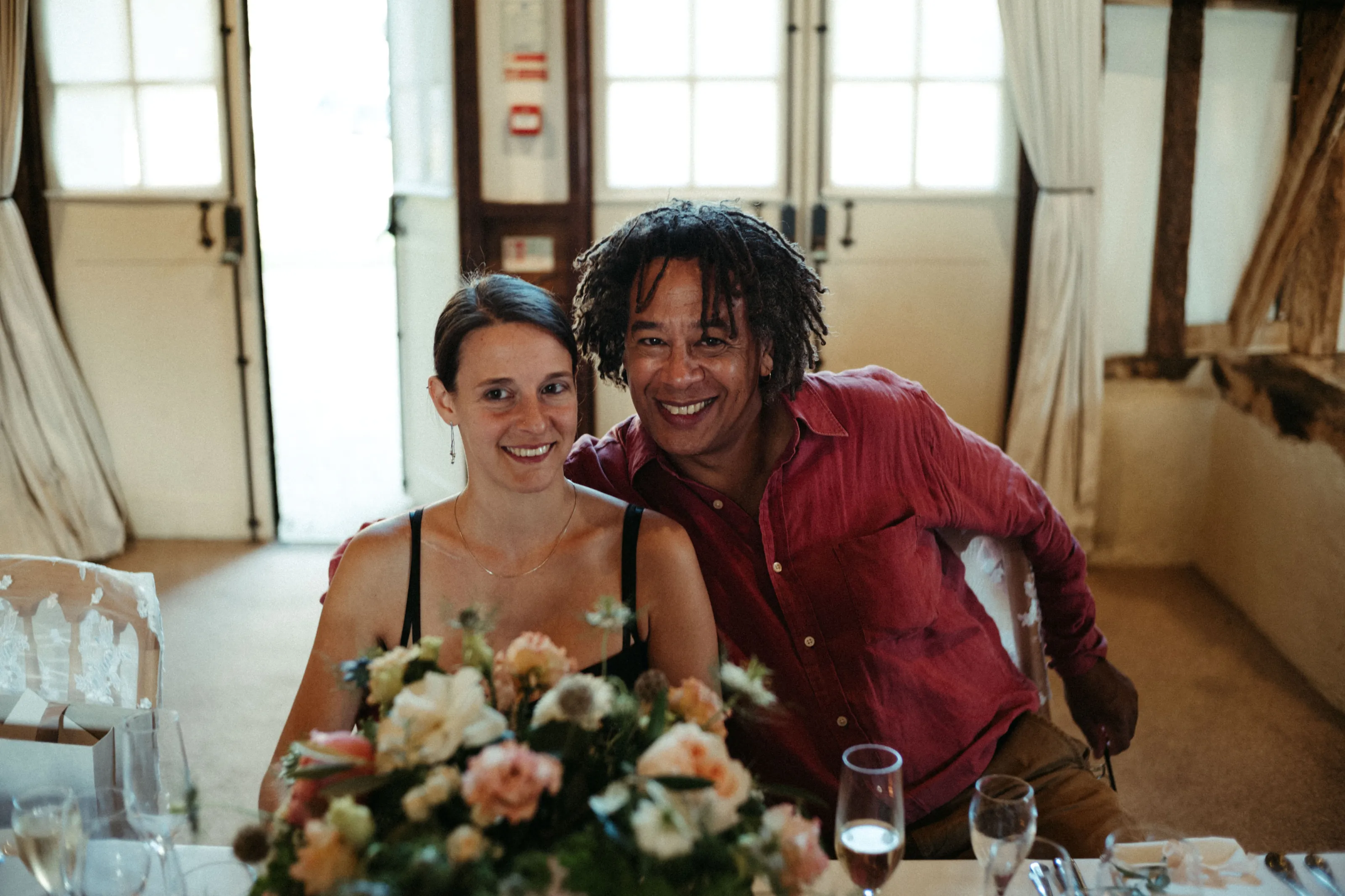 Smiling couple at a table with flowers and wine glasses.