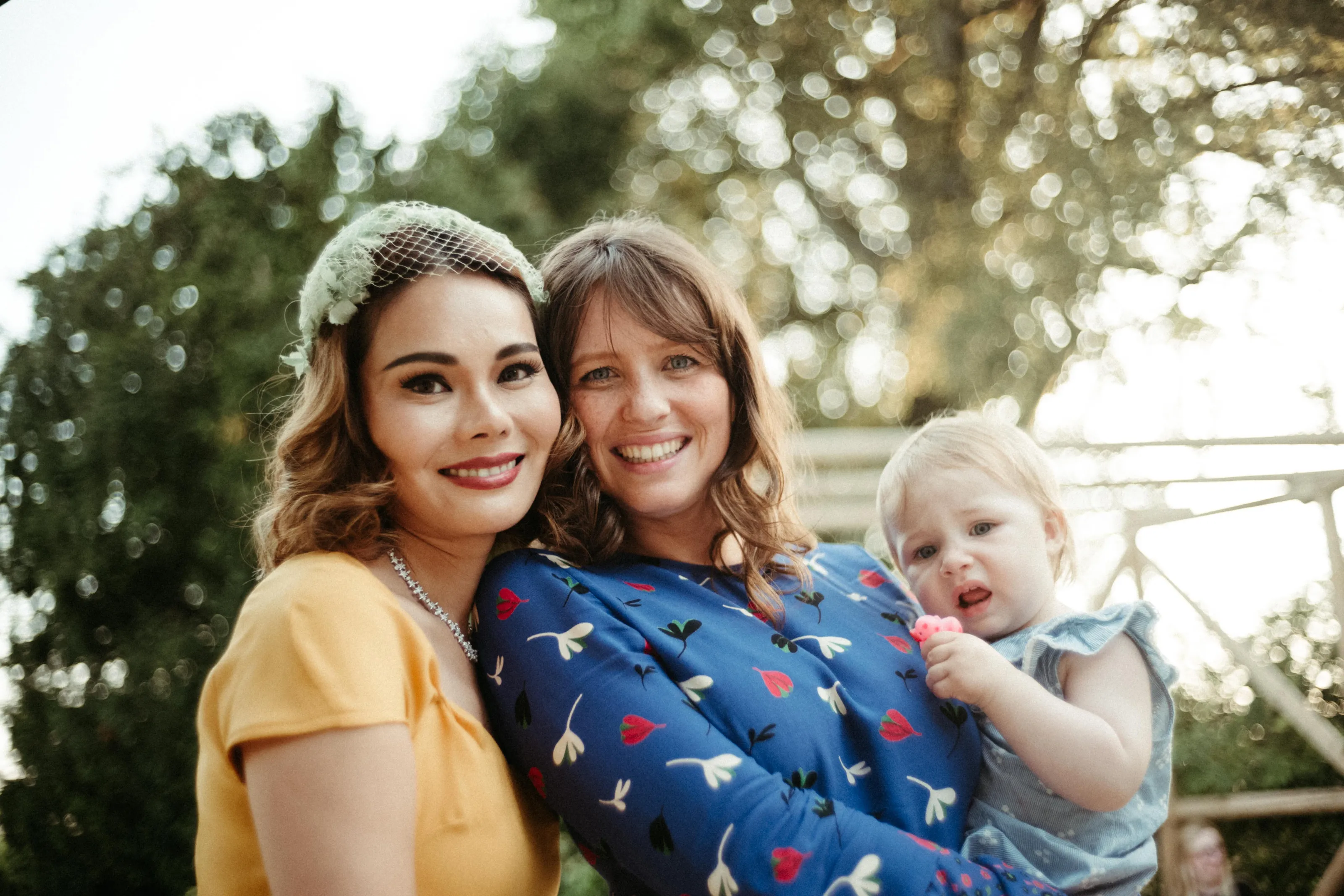 Smiling women and baby outdoors, one woman holding the child.