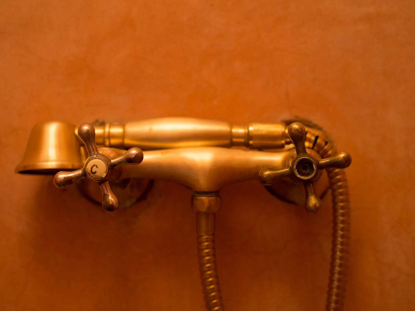 Vintage brass shower mixer tap with 'C' handle and hose.