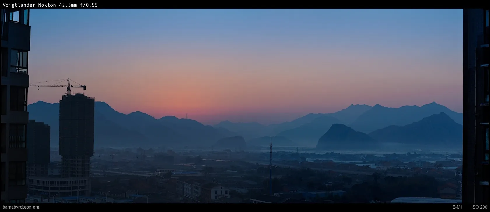 Town and misty mountains at sunrise, with a construction site.