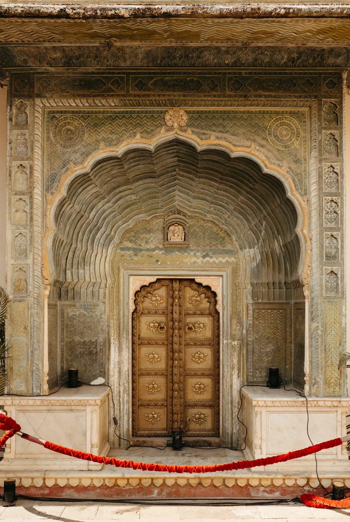 A small gilded double door set within deep layered stone arches and decorative carving.
