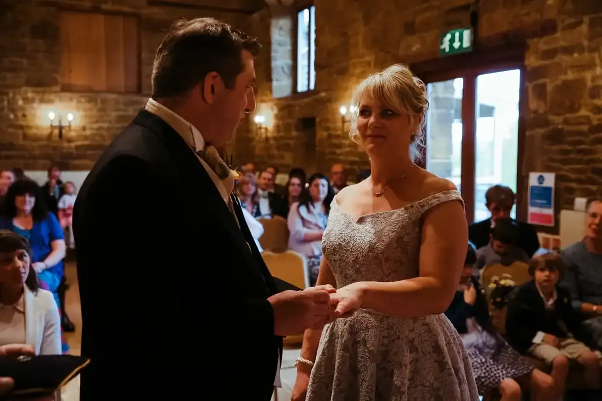Groom putting a wedding ring on his bride's finger.
