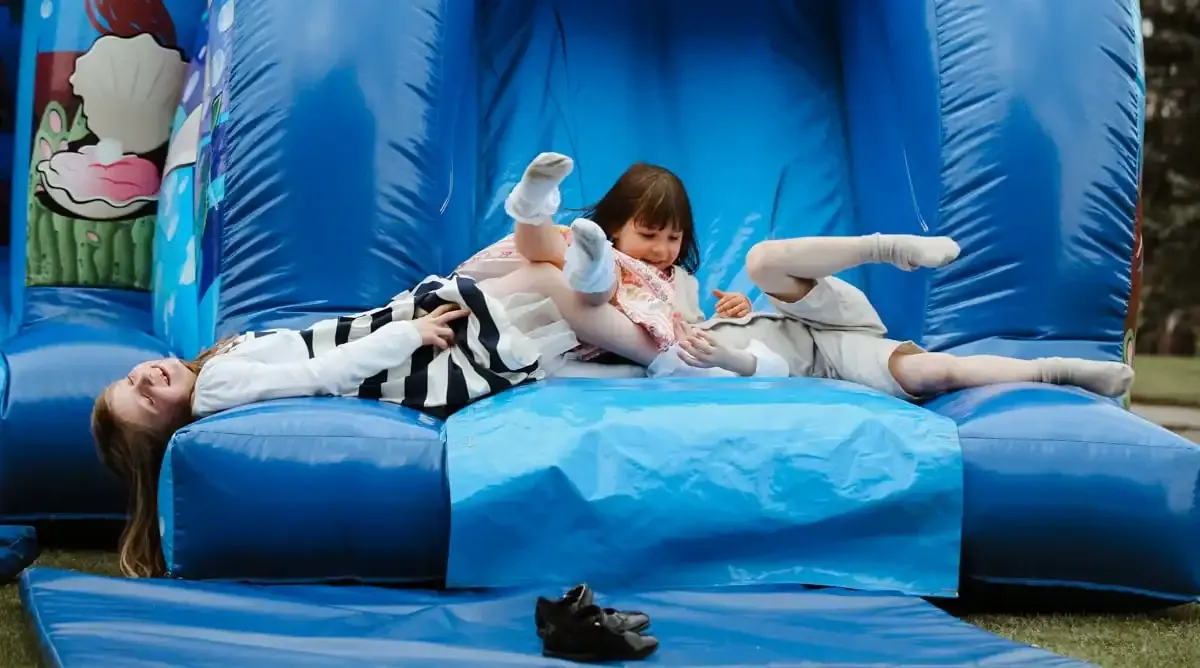 Three children playing on a blue bouncy castle.