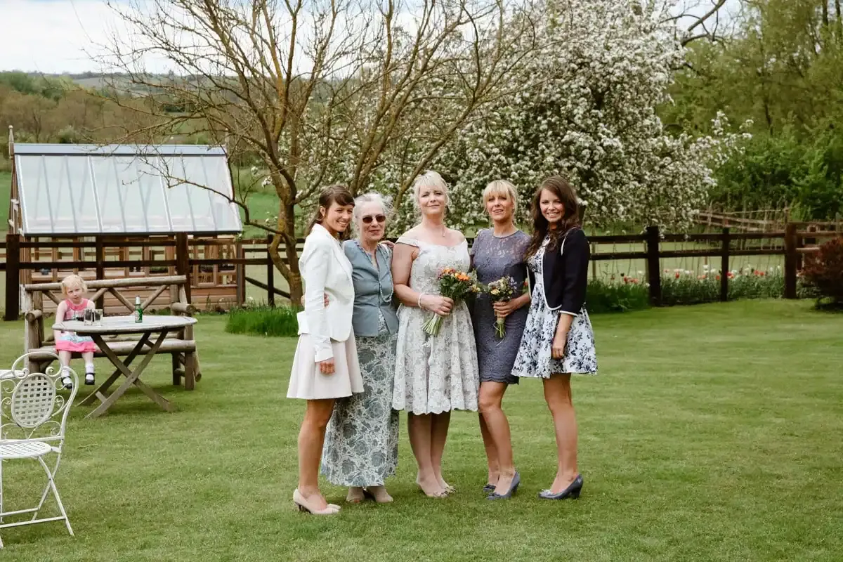 Five women, including a bride, and a child in a garden.