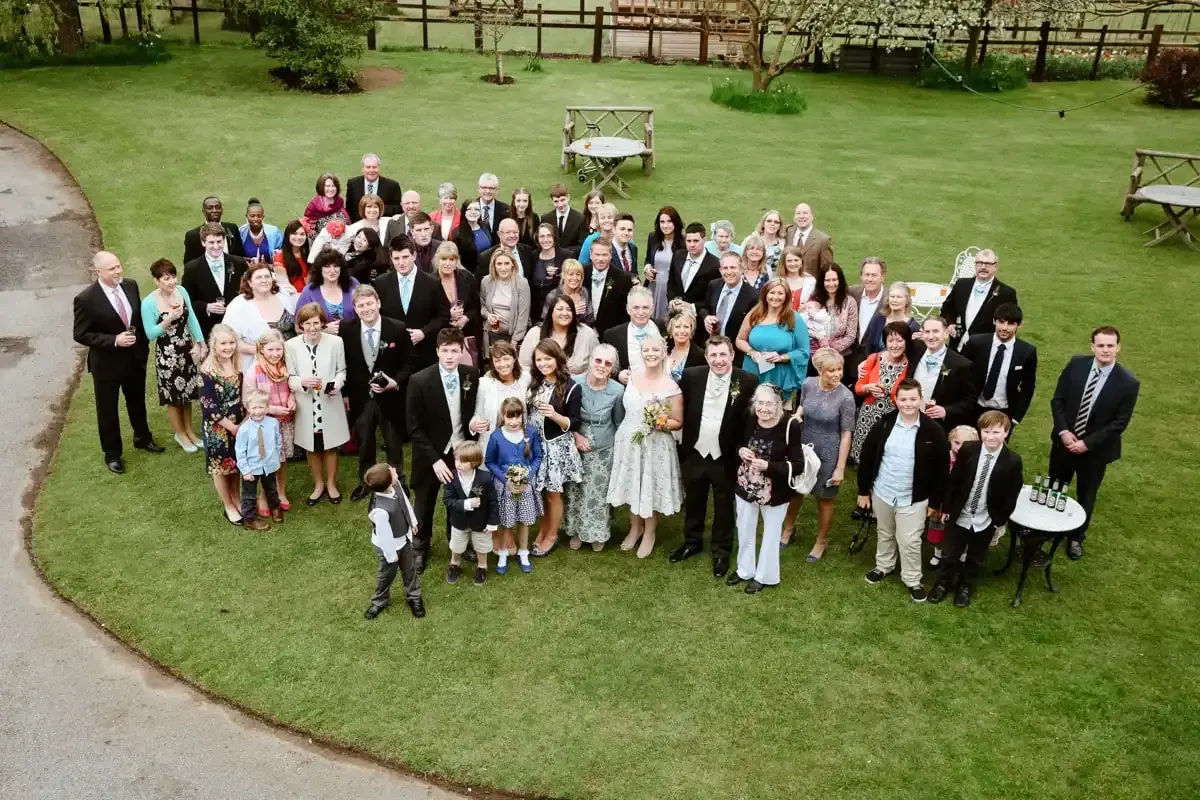 Formal group portrait of many adults and children on a green lawn.