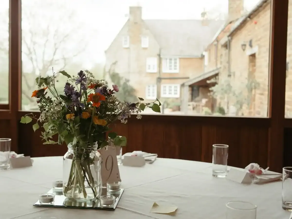 Wildflower centrepiece on a white table with tea lights, old brick buildings outside.