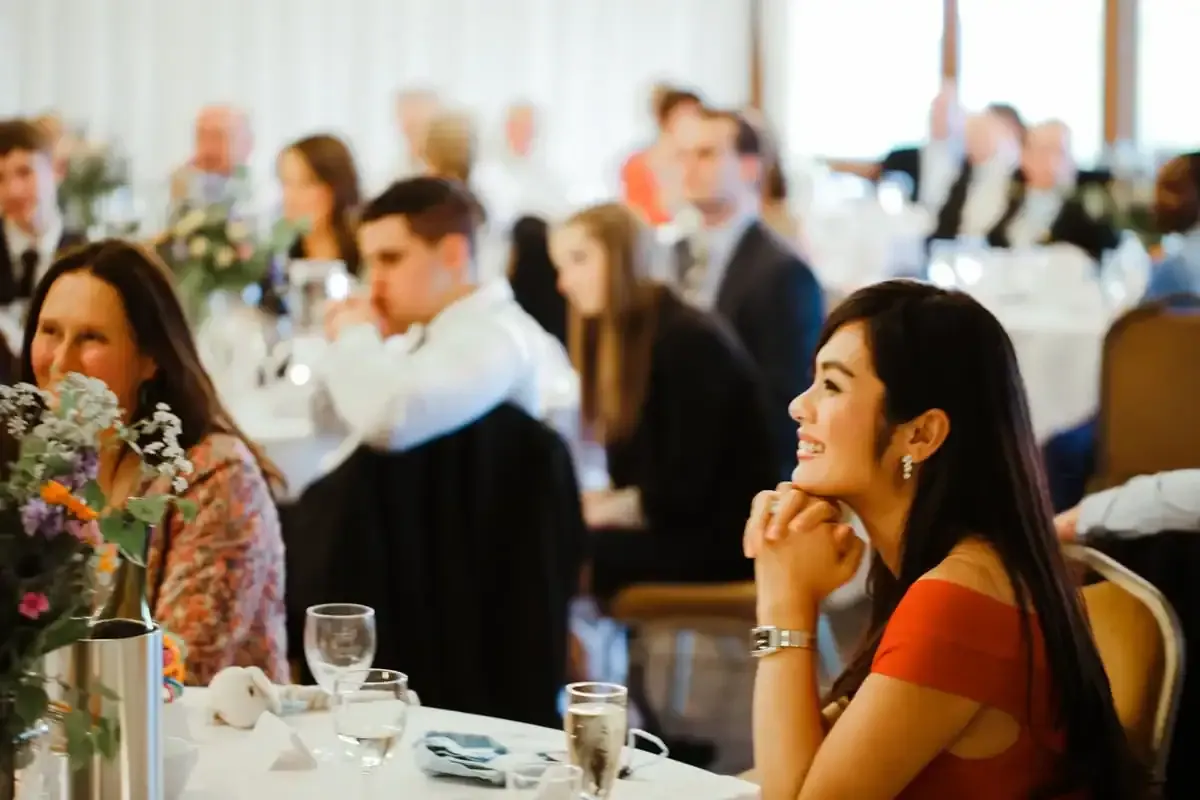 Smiling woman in red dress at a table with other guests.