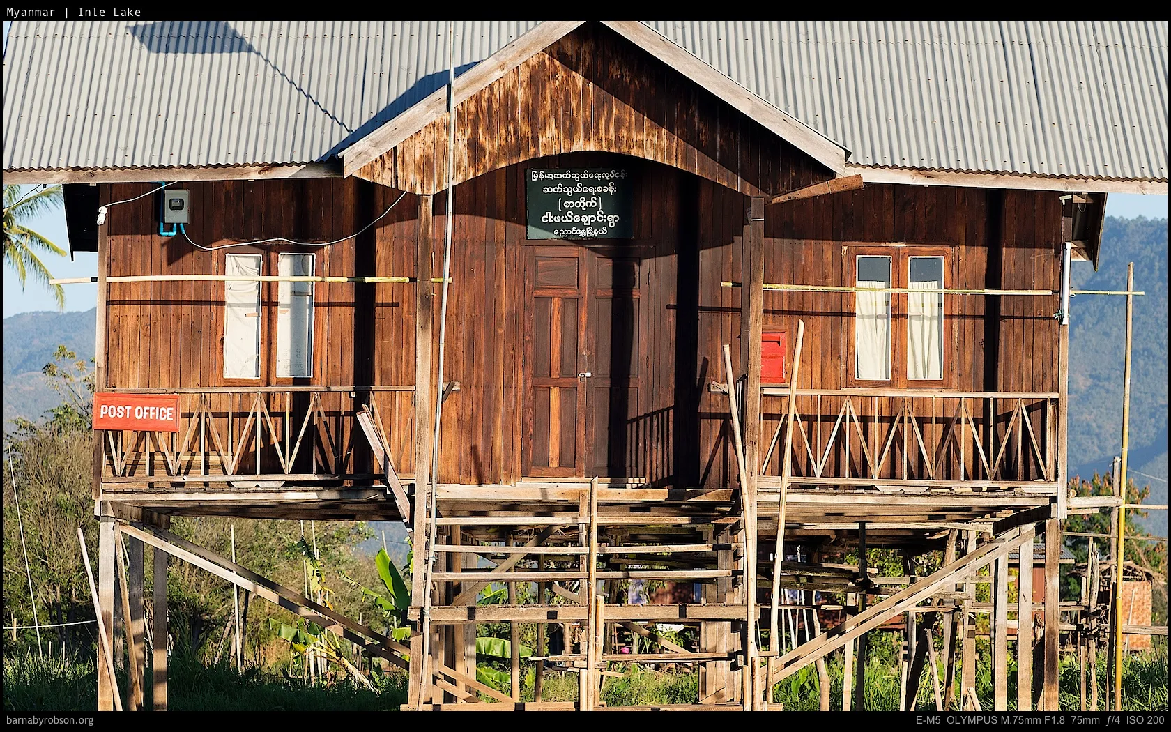 Wooden post office building on stilts with a corrugated roof.