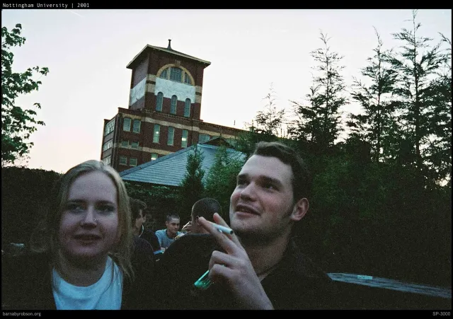 Two friends at dusk beneath a distant tower, shot on film.
