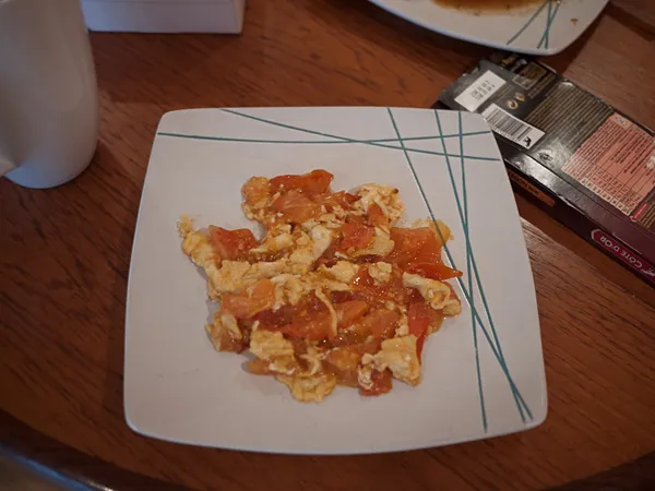 The finished fanqie chao dan: scrambled egg and tomato served on a patterned white plate.