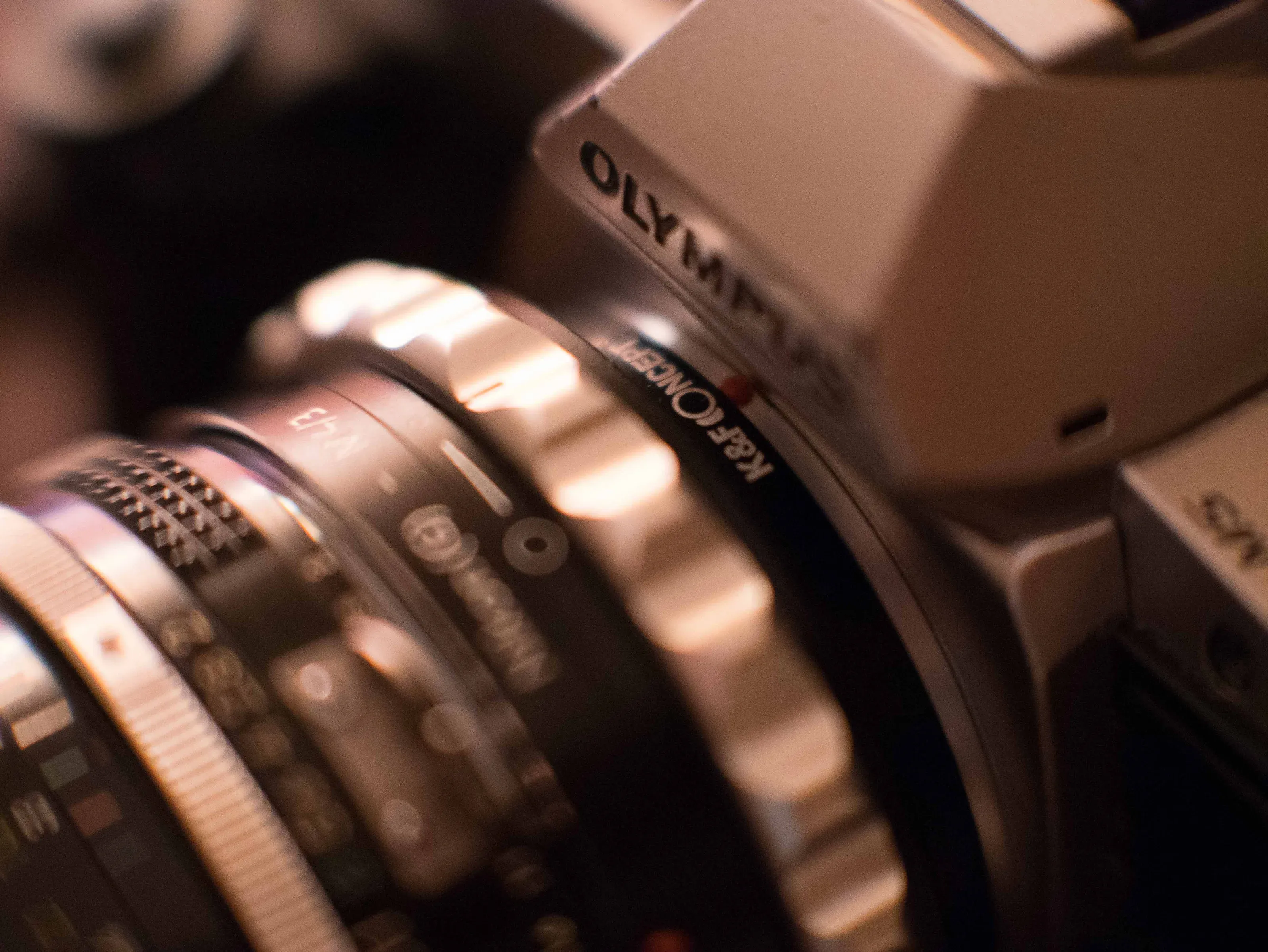 Close-up of the aperture ring on a legacy Nikon lens in warm light.