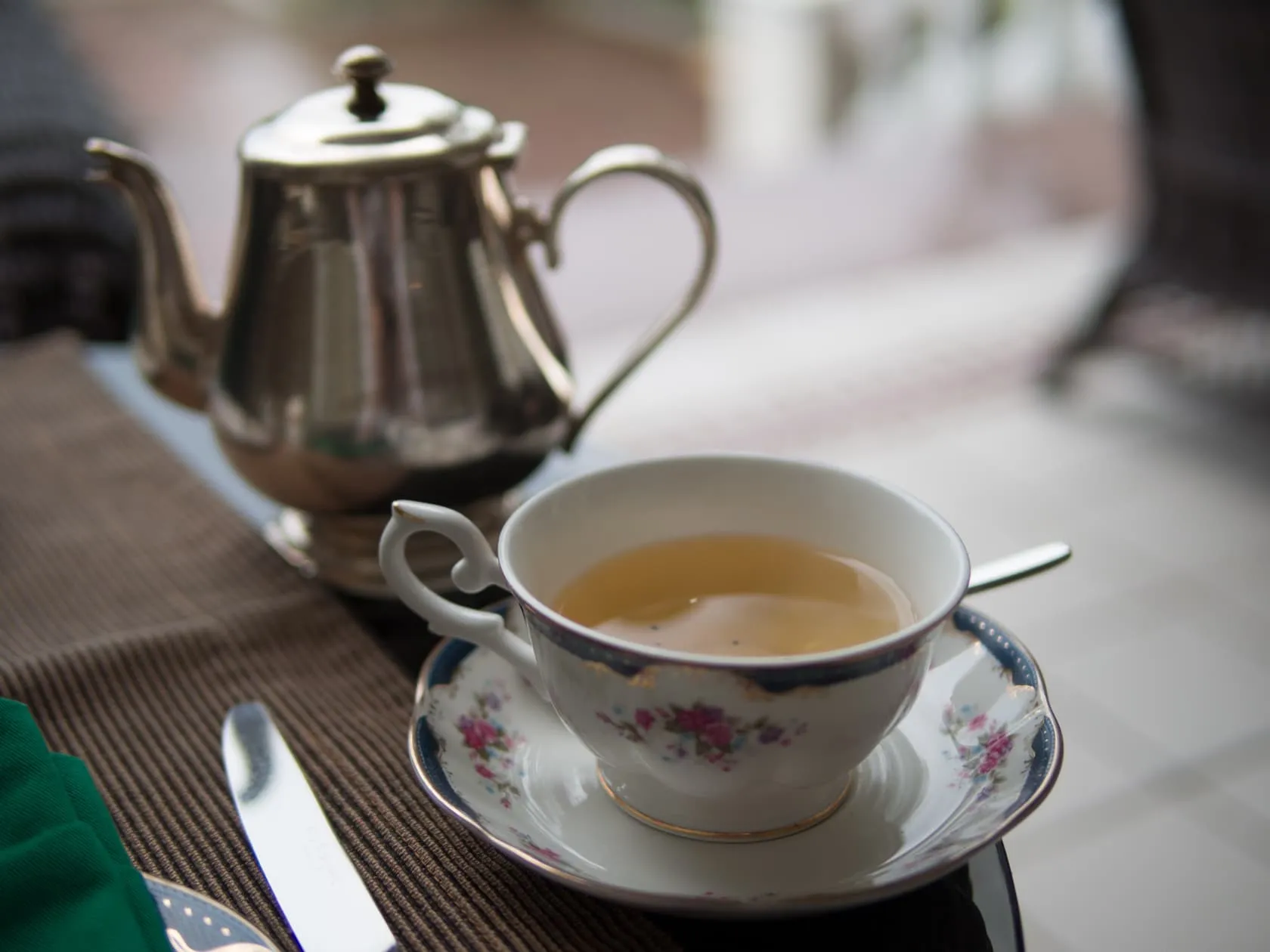 A cup of tea in floral china beside a silver teapot at Carcosa Seri Negara