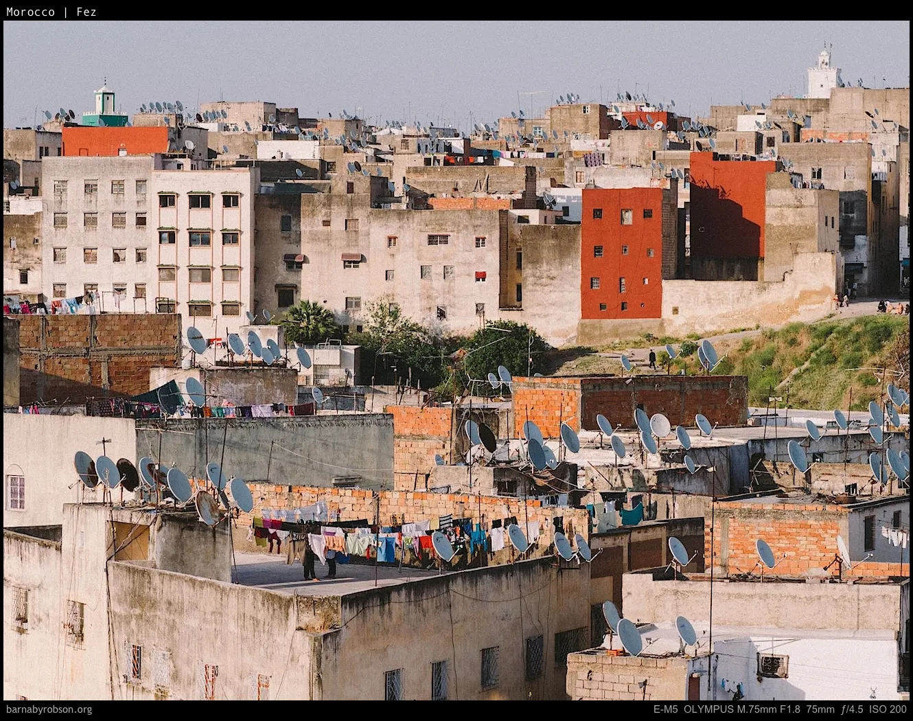Crowded Moroccan city rooftops with satellite dishes and laundry drying.