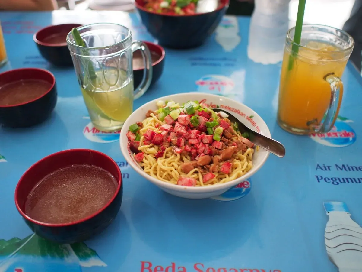 Medan-style pork noodles and iced drinks on a bright blue table in Tangerang.
