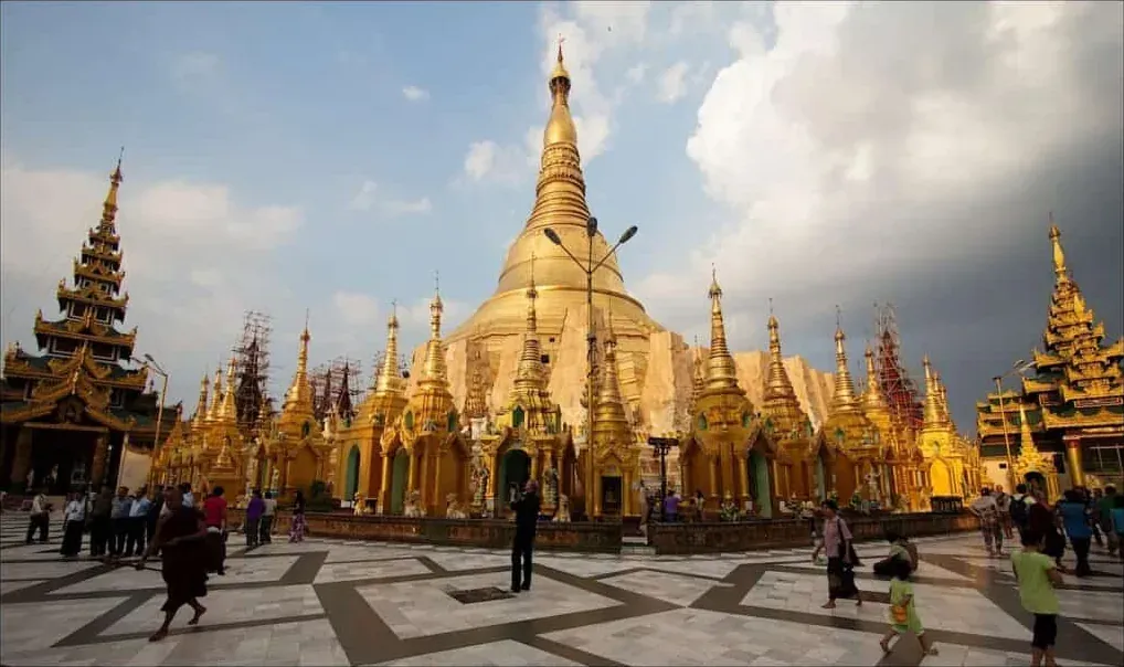 Shwedagon Paya: gold stupas and spires catching late sun under a storm-dark sky