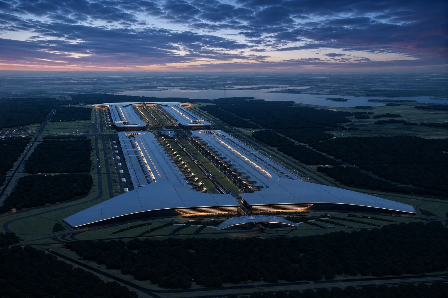 An illuminated hyperscale data-centre campus stretches through forest beneath a blue and pink dusk sky.