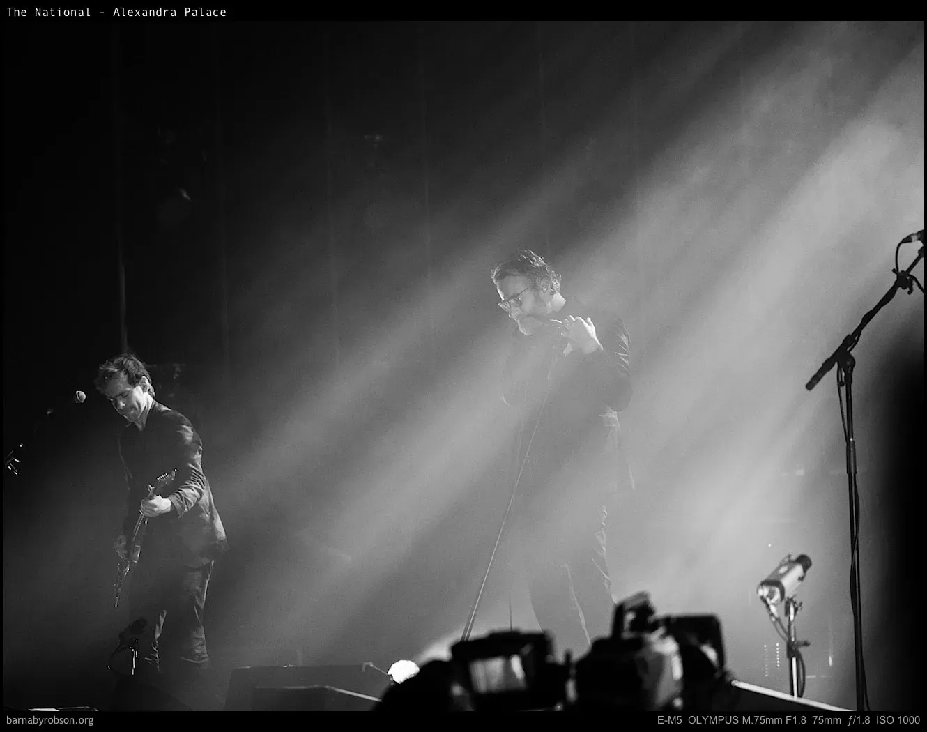 A stage light beam cutting through haze over The National, black and white.