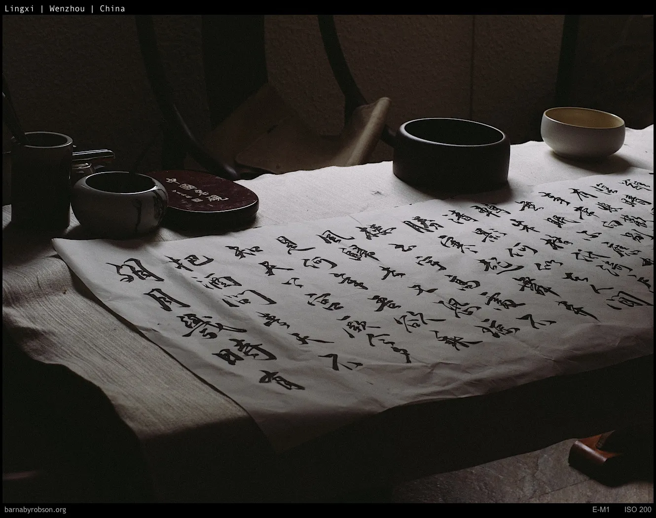 Traditional Chinese calligraphy on paper, with ink pots and ceramic bowls.