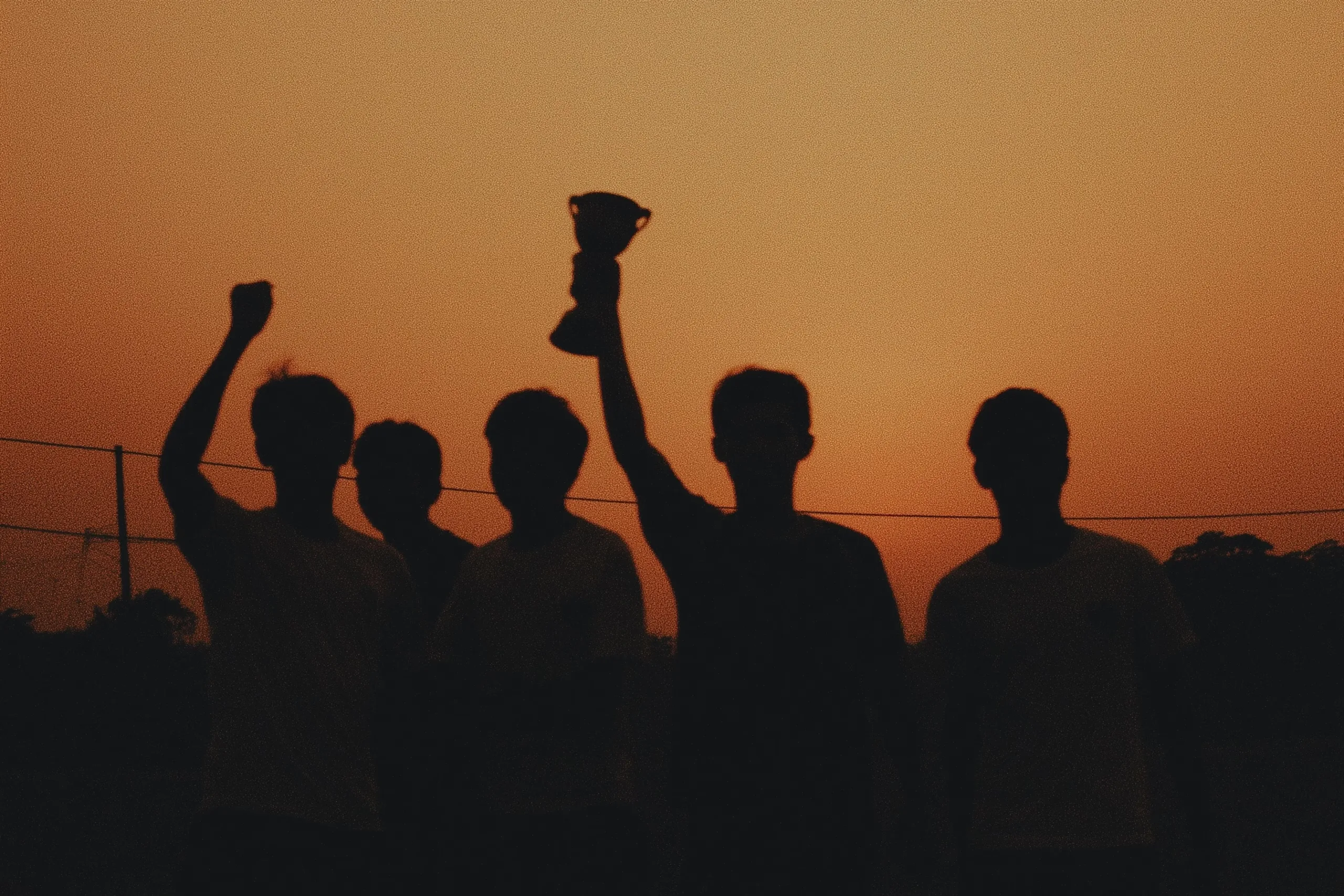 Silhouettes of people cheering against a sunset