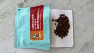 Rich, dark roasted coffee beans spilled from a resealable bag onto a white dotted surface, showcasing high-quality speciality coffee for coffee enthusiasts and connoisseurs, perfect for artisanal brewing.