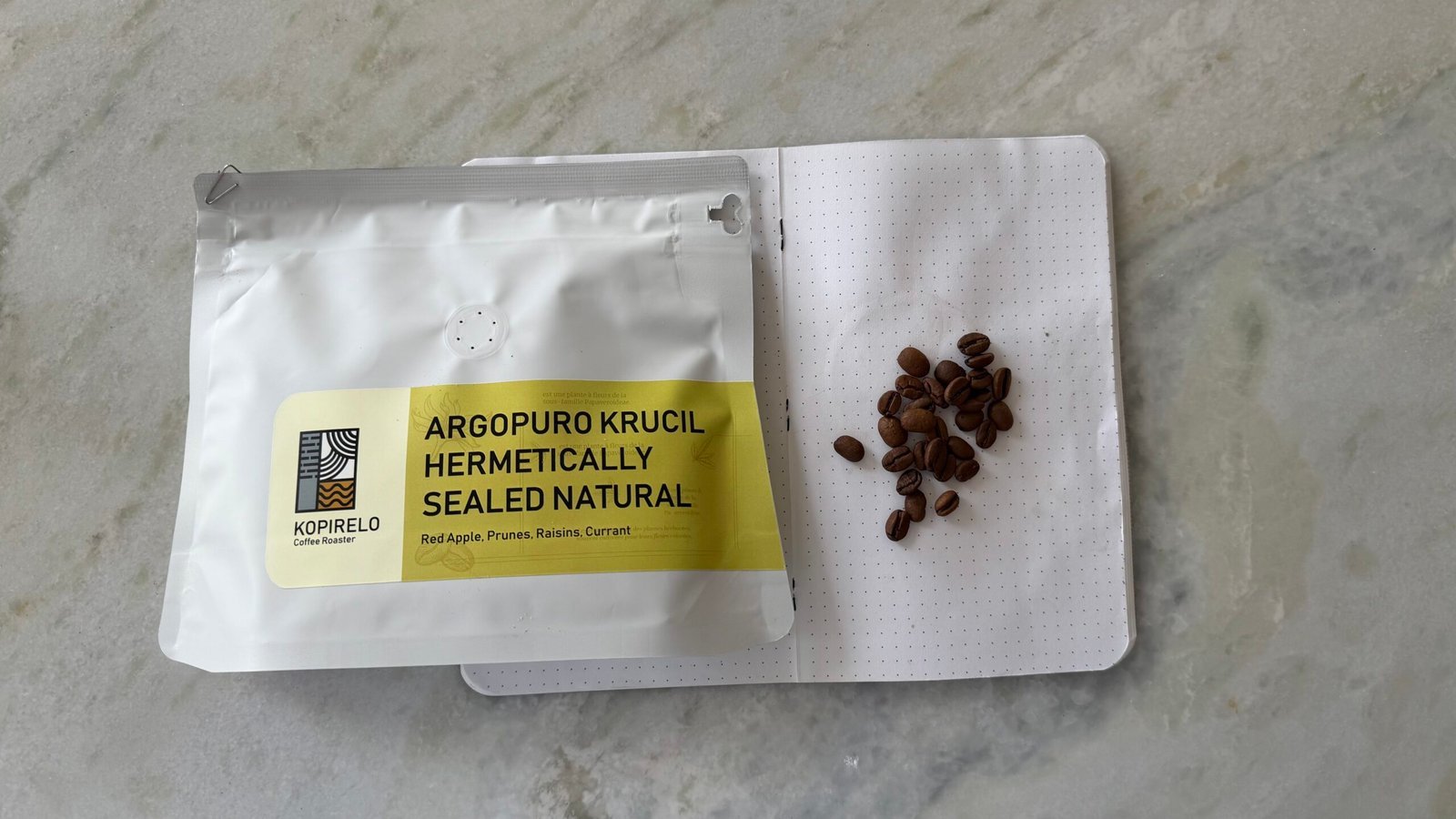 Argopuro Krucil natural coffee beans and sealed wild coffee package on marble surface for sustainable organic coffee brewing.