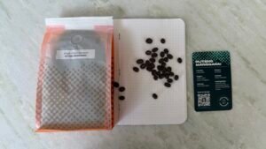 Rich, dark roasted single origin coffee beans from Ruteng Manggarai, Indonesia, shown alongside a tasting note card, for coffee enthusiasts and connoisseurs seeking authentic, high-quality Arabica beans.