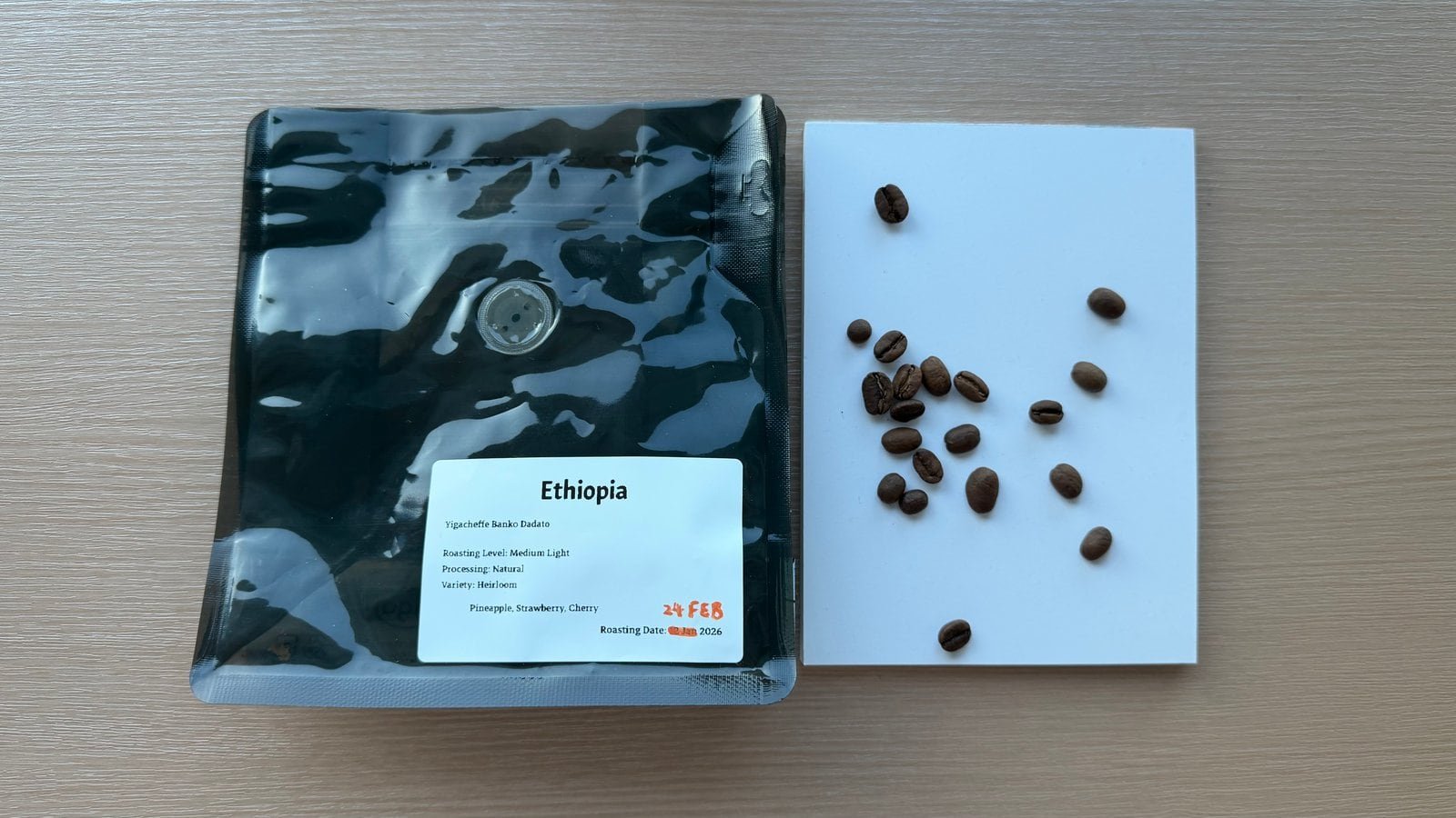 Close-up of roasted Ethiopia coffee beans on a white surface, with a black coffee bag labelled Ethiopia in the background.