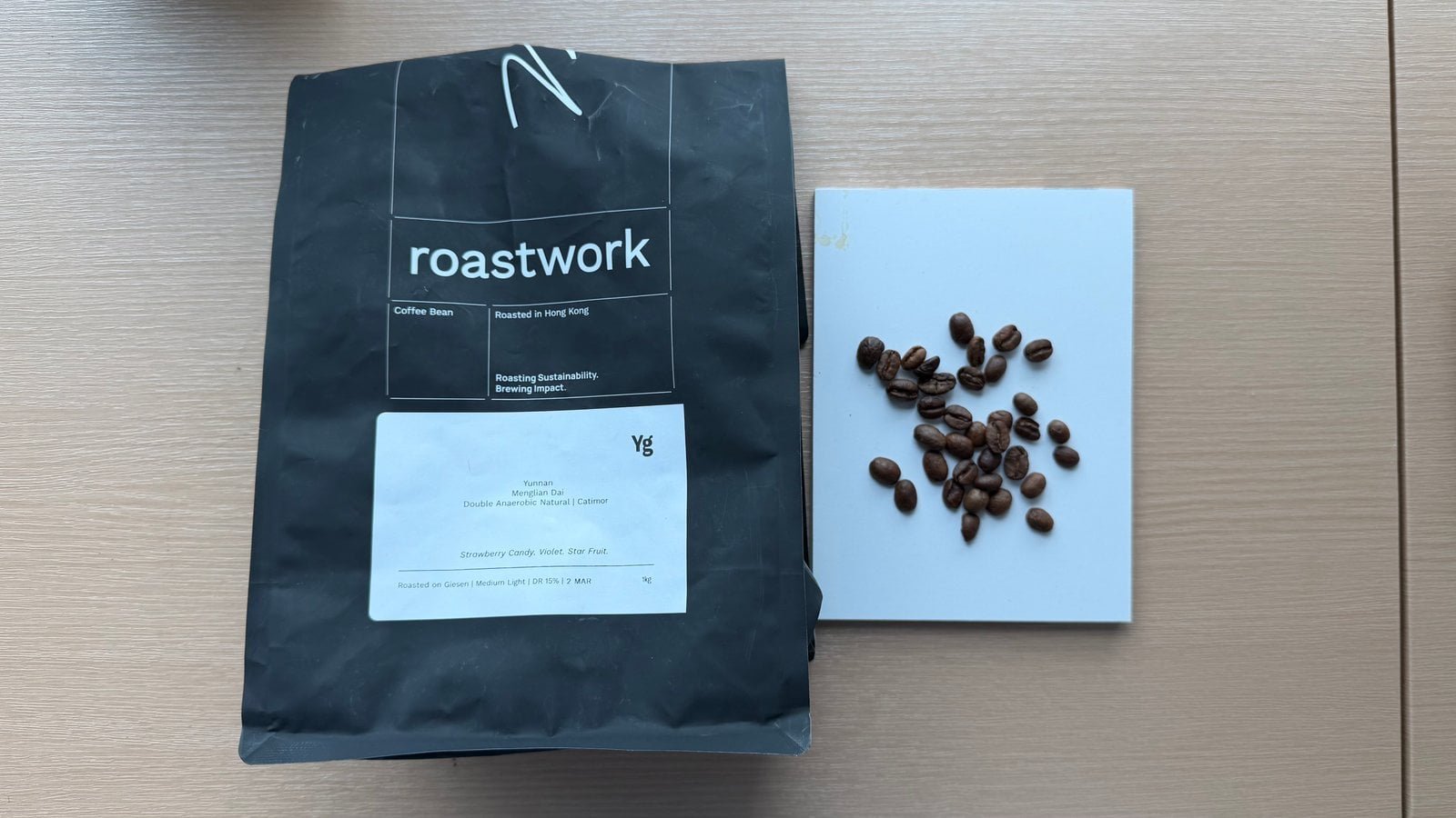 Coffee roasting bag with coffee beans on a white surface, showcasing artisanal coffee production.