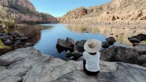 A traveller seated above a rocky gorge pool in Nitmiluk National Park.