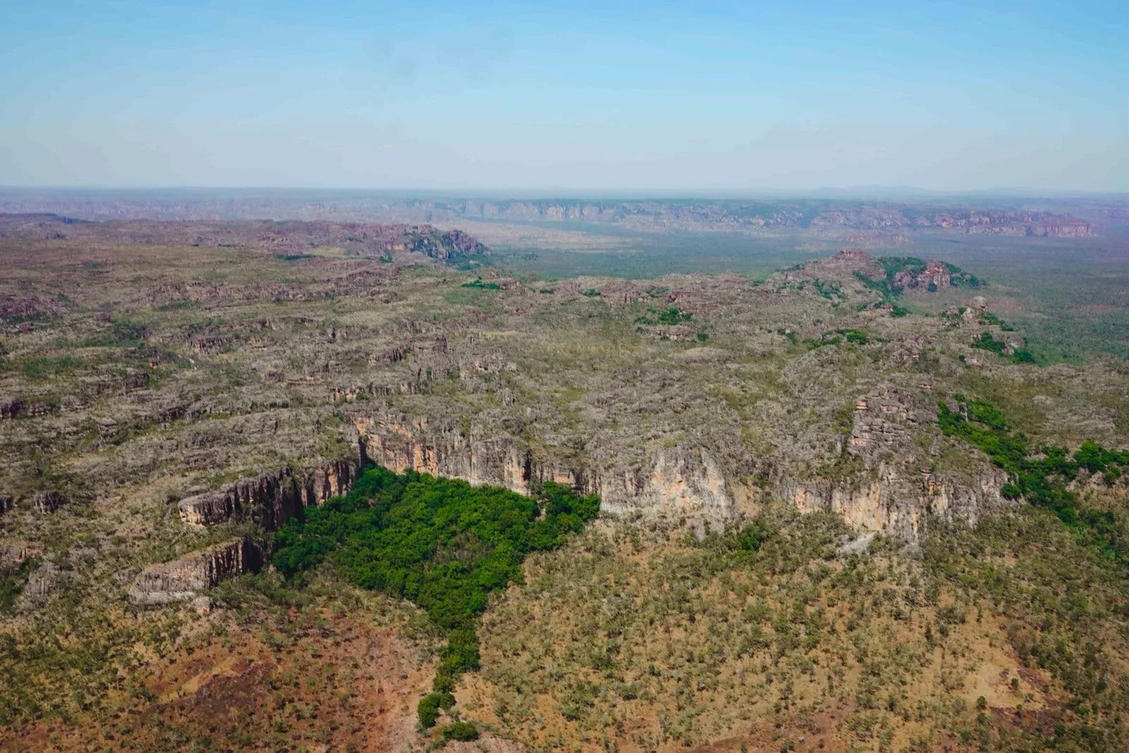 Rocky escarpment and green gullies seen from the air over Kakadu National Park.