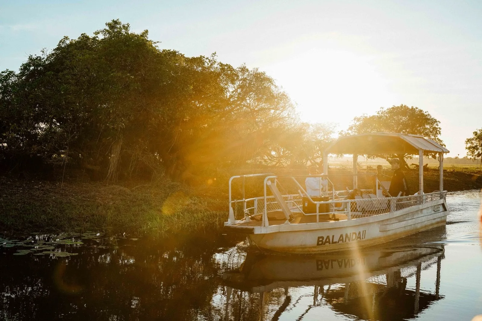 A cruise boat moving through golden light on Yellow Water in Kakadu.